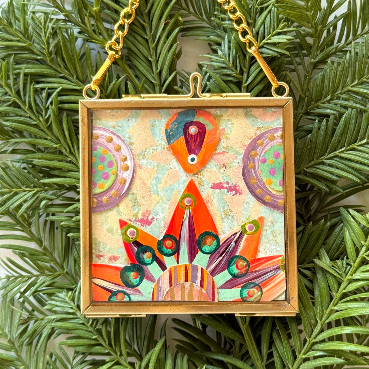 2.5" x 2.5" mixed-media collage is framed between glass in a petite brass hanging frame.