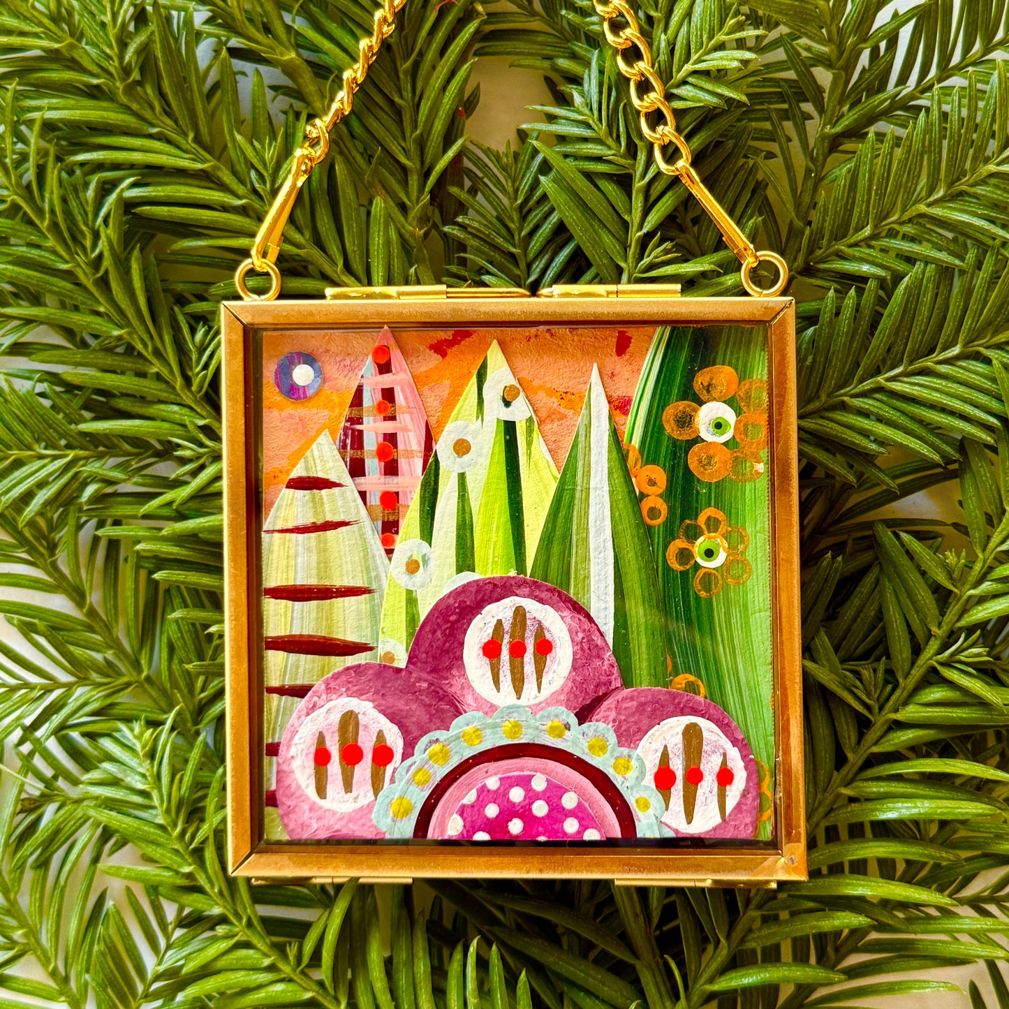 2.5" x 2.5" mixed-media collage is framed between glass in a petite brass hanging frame.