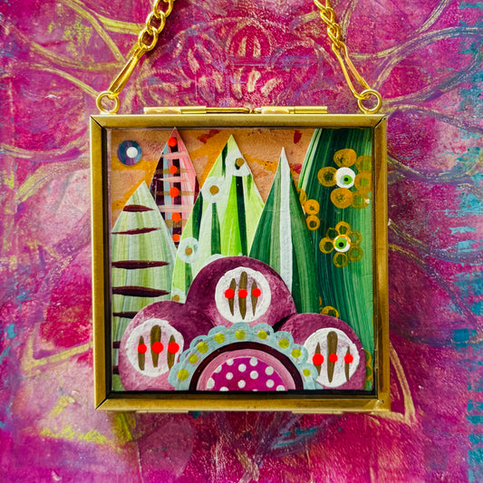 2.5" x 2.5" mixed-media collage is framed between glass in a petite brass hanging frame.