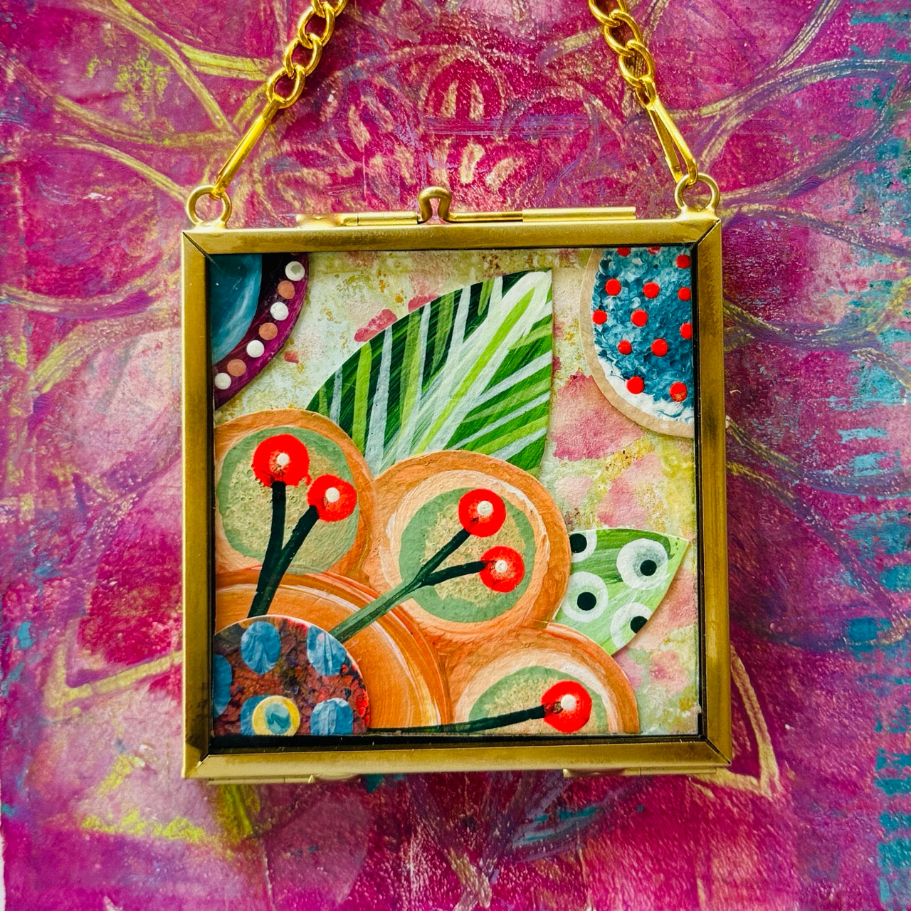 2.5" x 2.5" mixed-media collage is framed between glass in a petite brass hanging frame.
