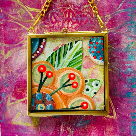 2.5" x 2.5" mixed-media collage is framed between glass in a petite brass hanging frame.