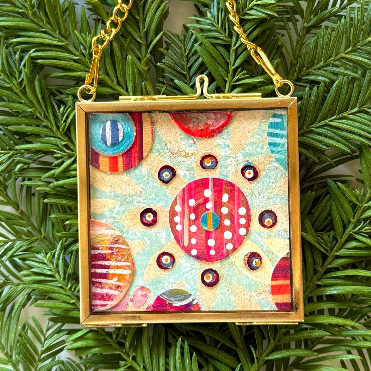 2.5" x 2.5" mixed-media collage is framed between glass in a petite brass hanging frame.