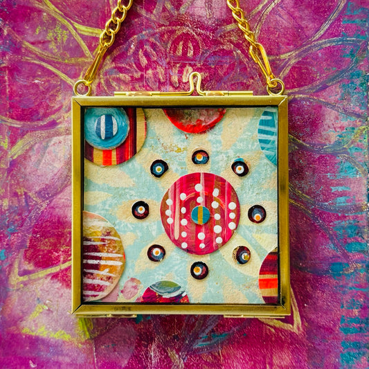 2.5" x 2.5" mixed-media collage is framed between glass in a petite brass hanging frame.