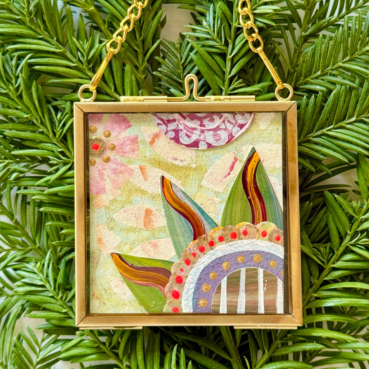 2.5" x 2.5" mixed-media collage is framed between glass in a petite brass hanging frame.