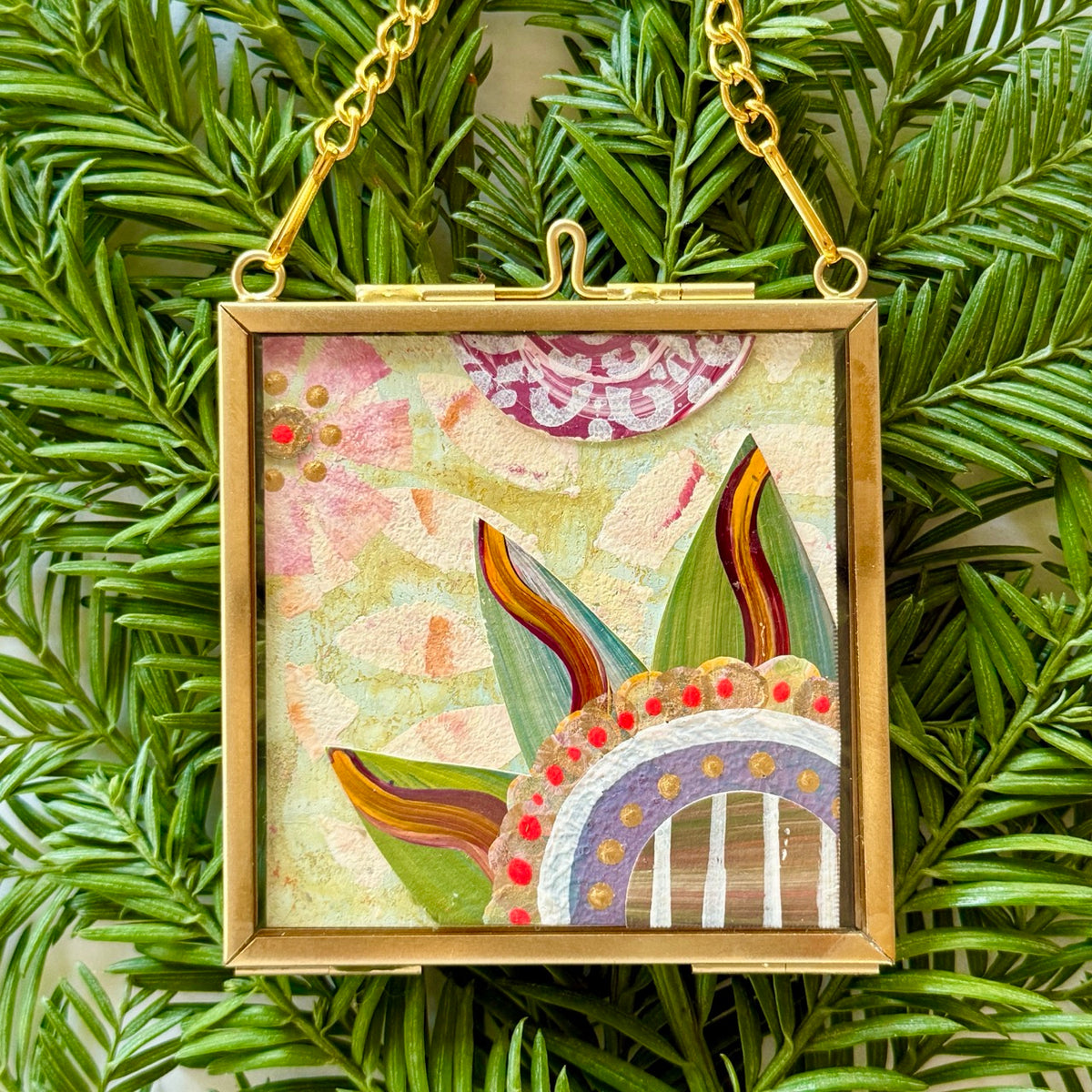 2.5" x 2.5" mixed-media collage is framed between glass in a petite brass hanging frame.