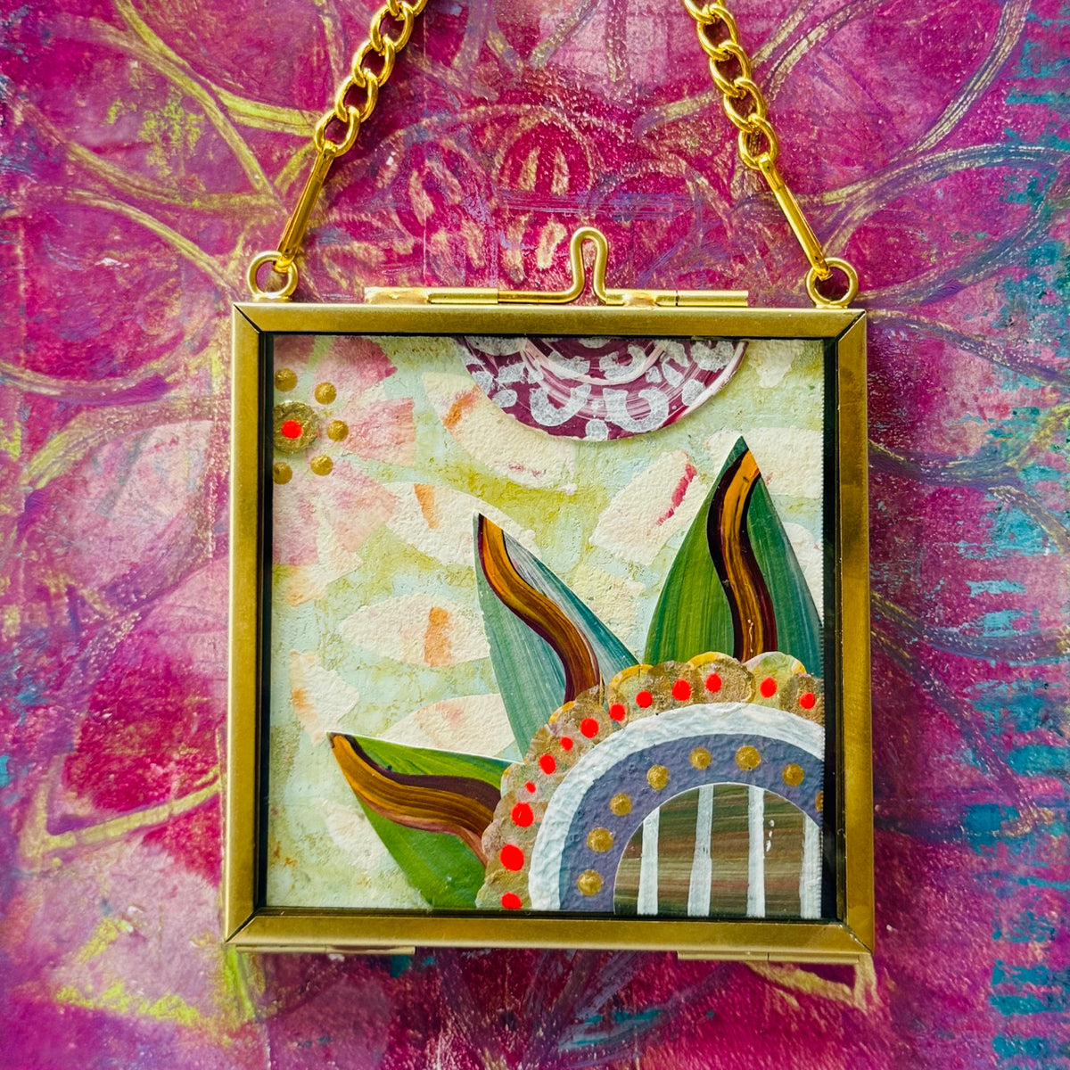 2.5" x 2.5" mixed-media collage is framed between glass in a petite brass hanging frame.