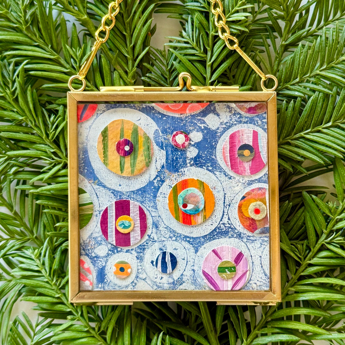 2.5" x 2.5" mixed-media collage is framed between glass in a petite brass hanging frame.
