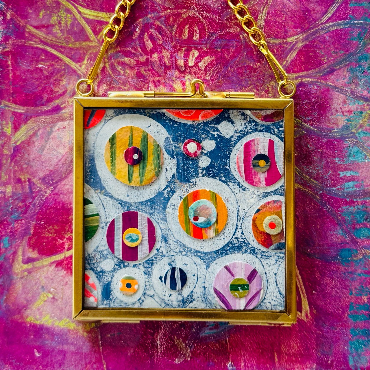 2.5" x 2.5" mixed-media collage is framed between glass in a petite brass hanging frame.