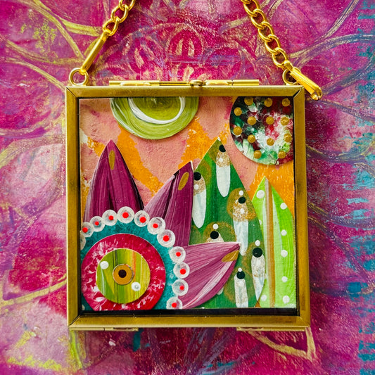 2.5" x 2.5" mixed-media collage is framed between glass in a petite brass hanging frame.
