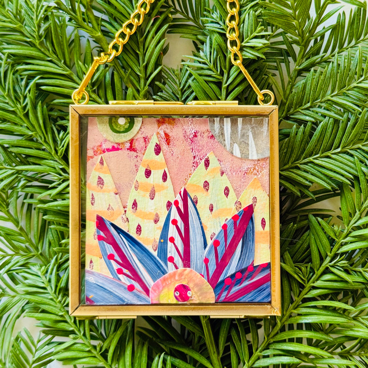 2.5" x 2.5" mixed-media collage is framed between glass in a petite brass hanging frame.
