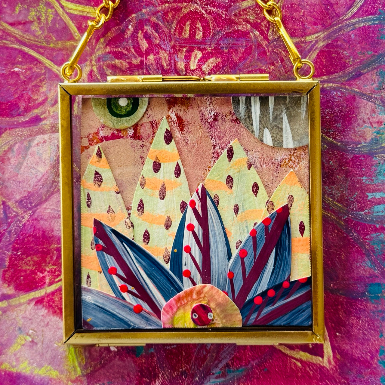 2.5" x 2.5" mixed-media collage is framed between glass in a petite brass hanging frame.