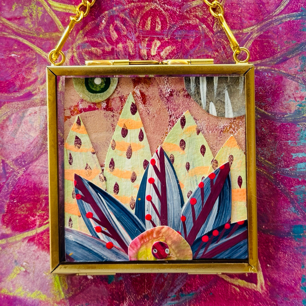 2.5" x 2.5" mixed-media collage is framed between glass in a petite brass hanging frame.