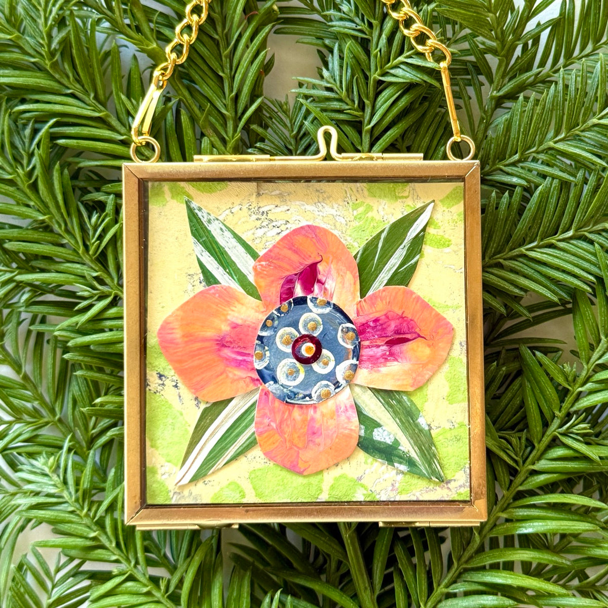 2.5" x 2.5" mixed-media collage is framed between glass in a petite brass hanging frame.