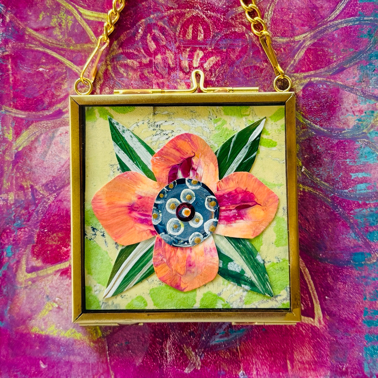 2.5" x 2.5" mixed-media collage is framed between glass in a petite brass hanging frame.