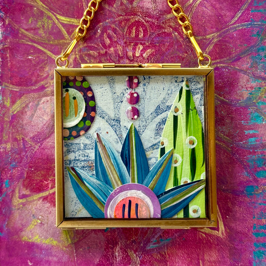 2.5" x 2.5" mixed-media collage is framed between glass in a petite brass hanging frame.