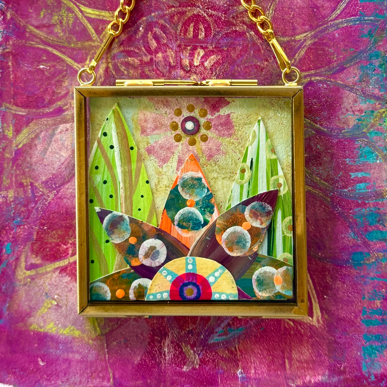 2.5" x 2.5" mixed-media collage is framed between glass in a petite brass hanging frame.