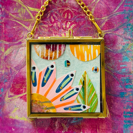 2.5" x 2.5" mixed-media collage is framed between glass in a petite brass hanging frame.