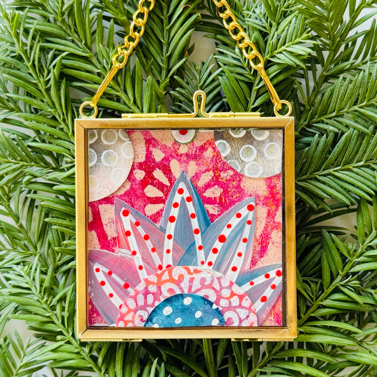2.5" x 2.5" mixed-media collage is framed between glass in a petite brass hanging frame.