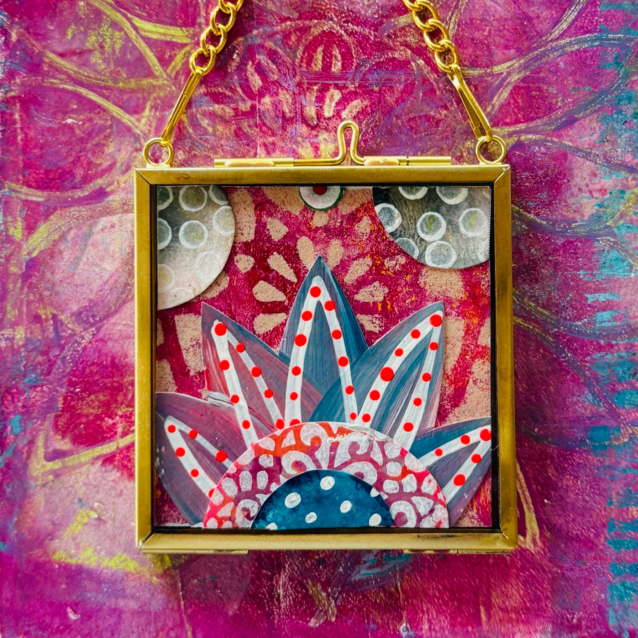 2.5" x 2.5" mixed-media collage is framed between glass in a petite brass hanging frame.