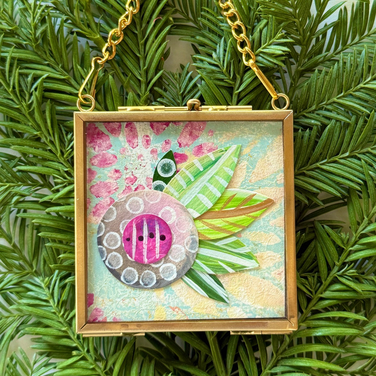 2.5" x 2.5" mixed-media collage is framed between glass in a petite brass hanging frame.