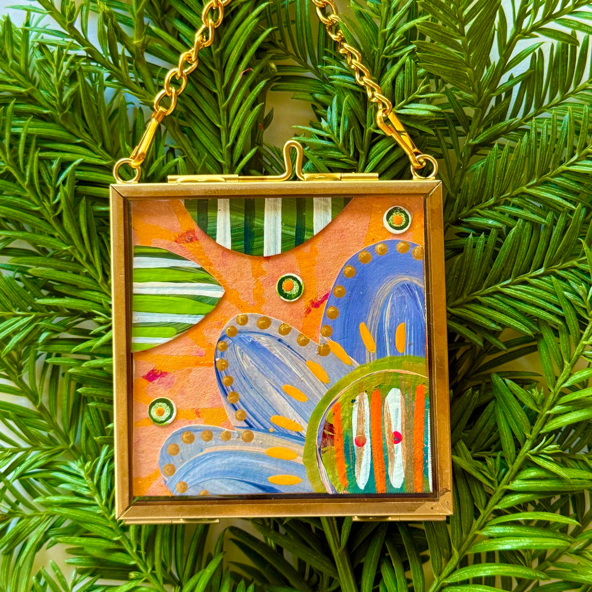 2.5" x 2.5" mixed-media collage is framed between glass in a petite brass hanging frame.