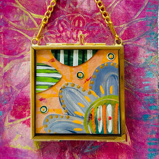 2.5" x 2.5" mixed-media collage is framed between glass in a petite brass hanging frame.
