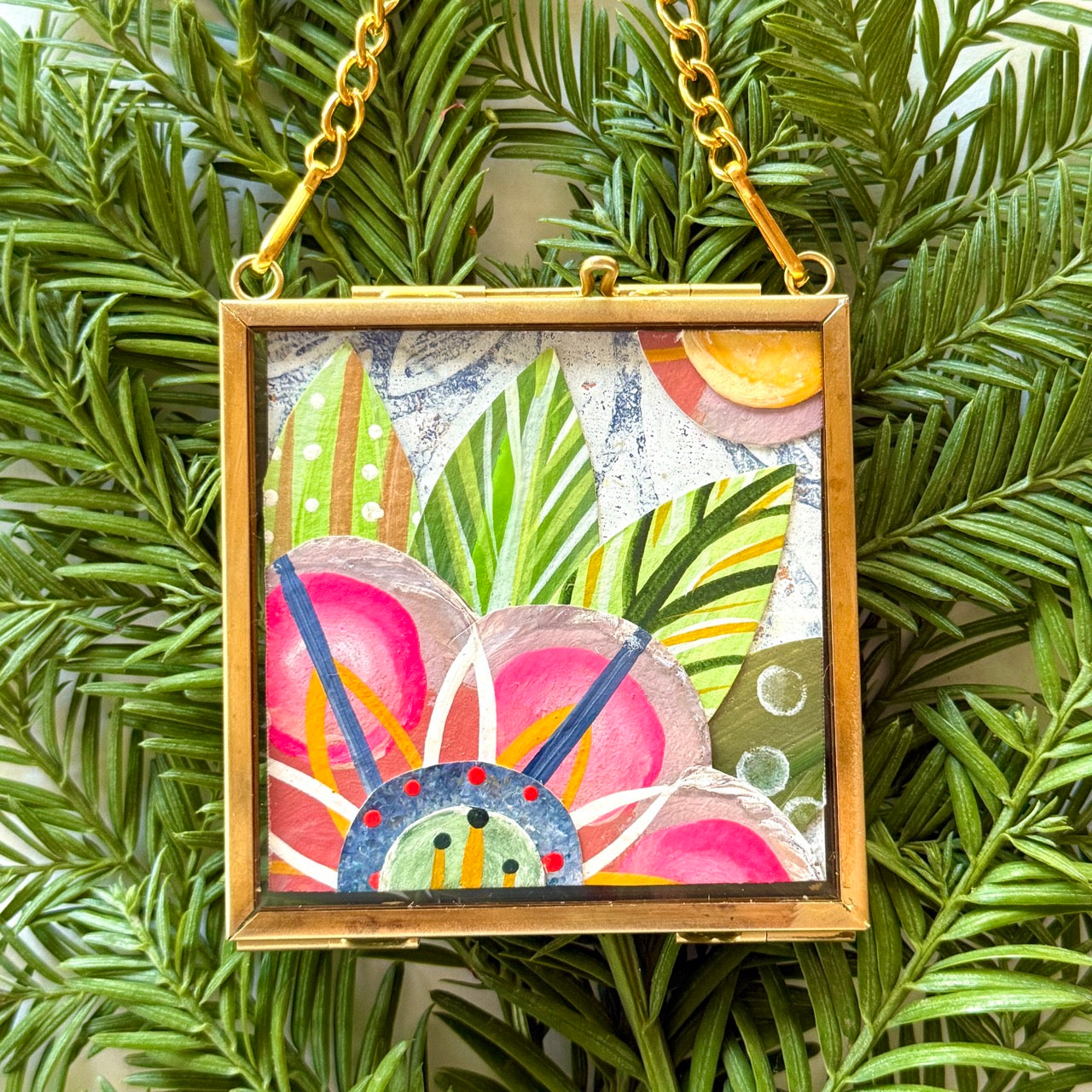 2.5" x 2.5" mixed-media collage is framed between glass in a petite brass hanging frame.