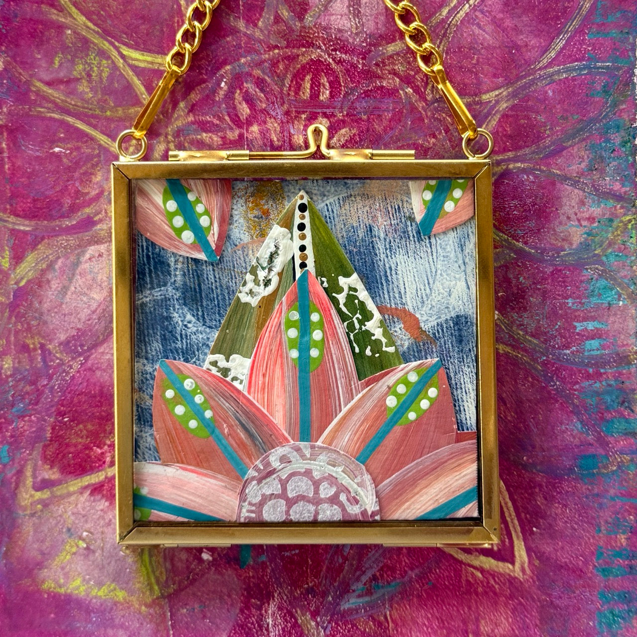 2.5" x 2.5" mixed-media collage is framed between glass in a petite brass hanging frame.