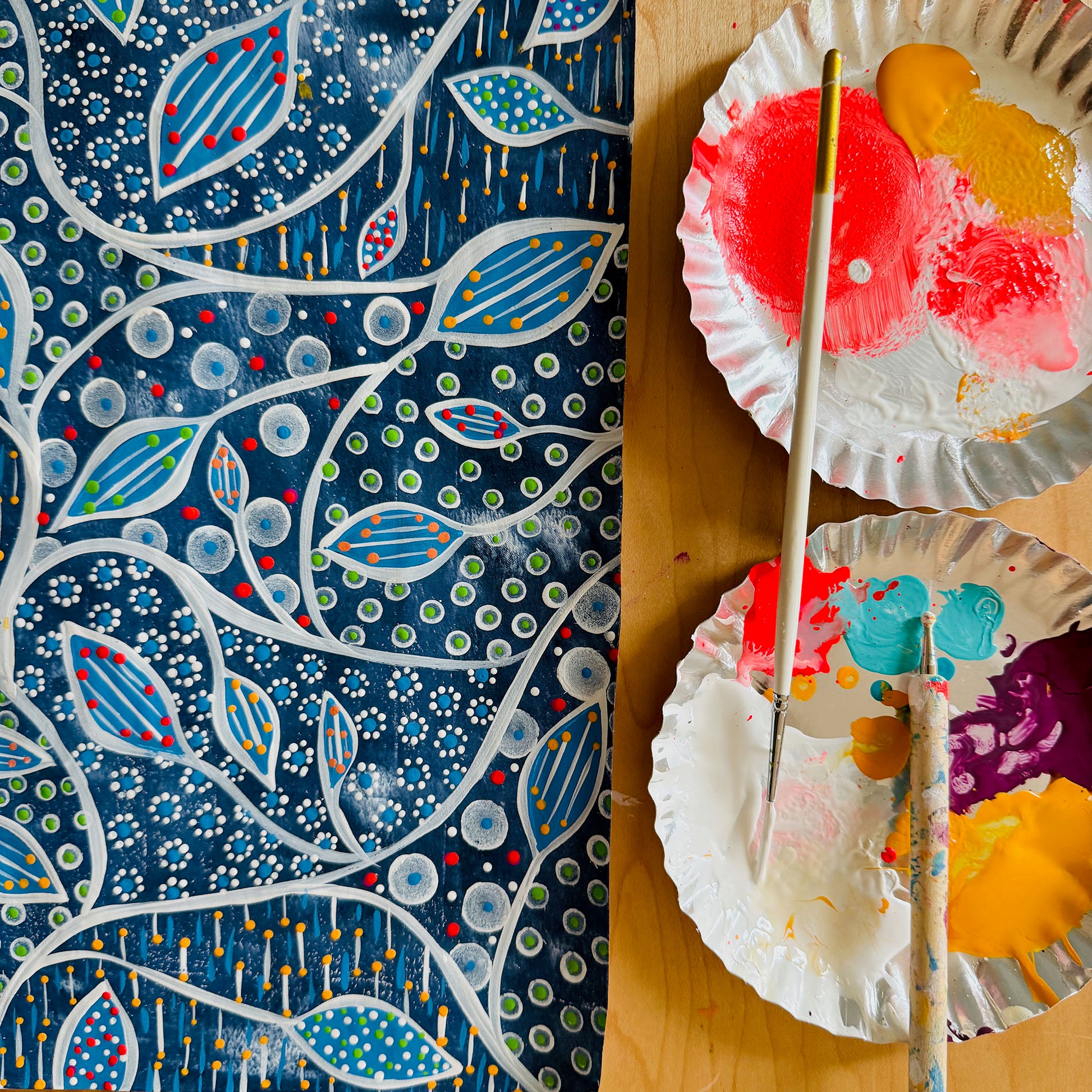 Colorful abstract painting on a textured surface with paintbrushes and a palette.