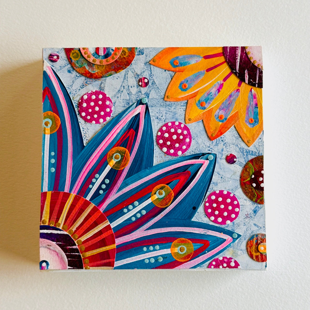 Small square wood panel art with a bold patterned floral design and hand-painted collage elements.