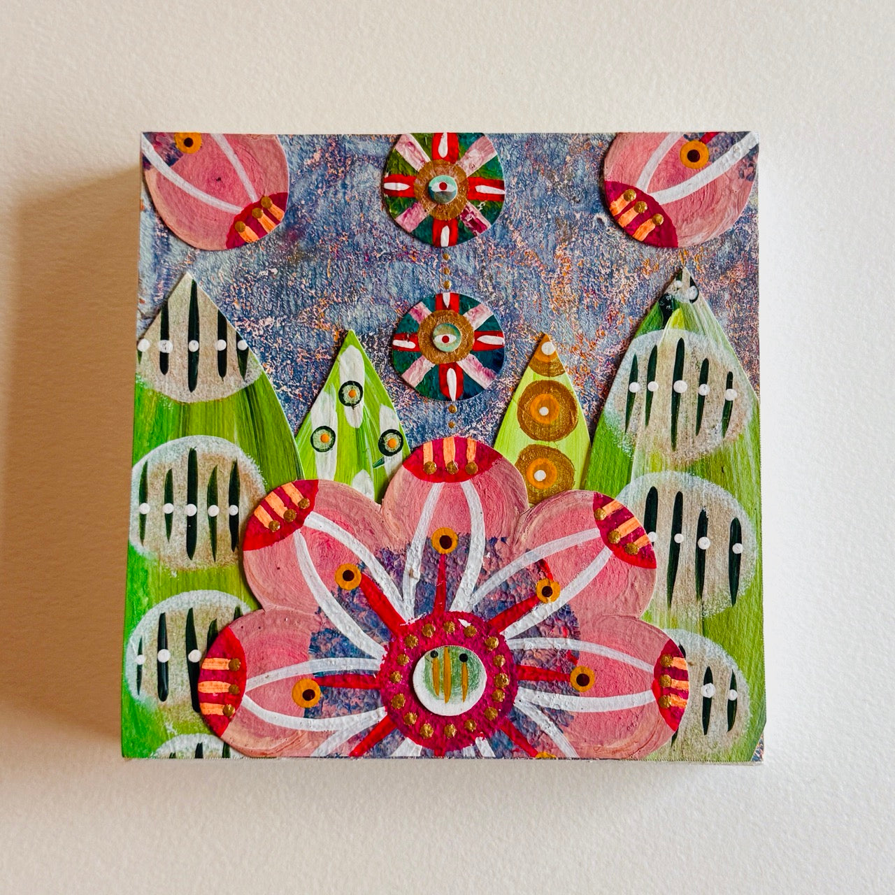 Small square wood panel art with a bold patterned floral design and hand-painted collage elements.