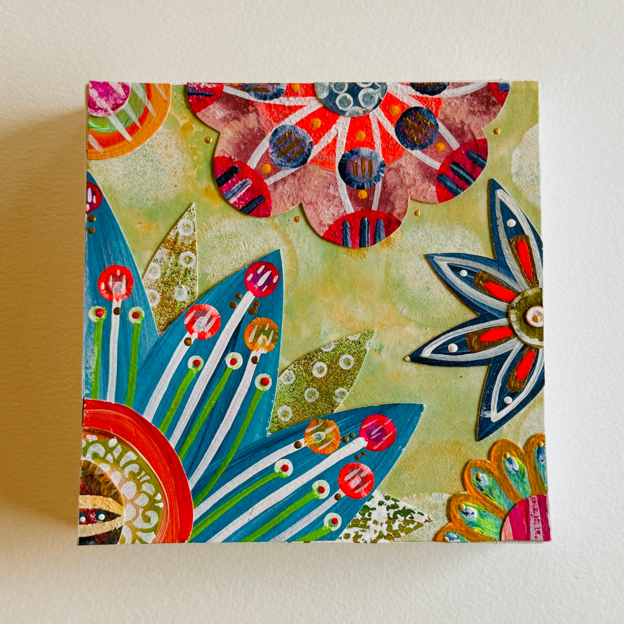 Small square wood panel art with a bold patterned floral design and hand-painted collage elements.
