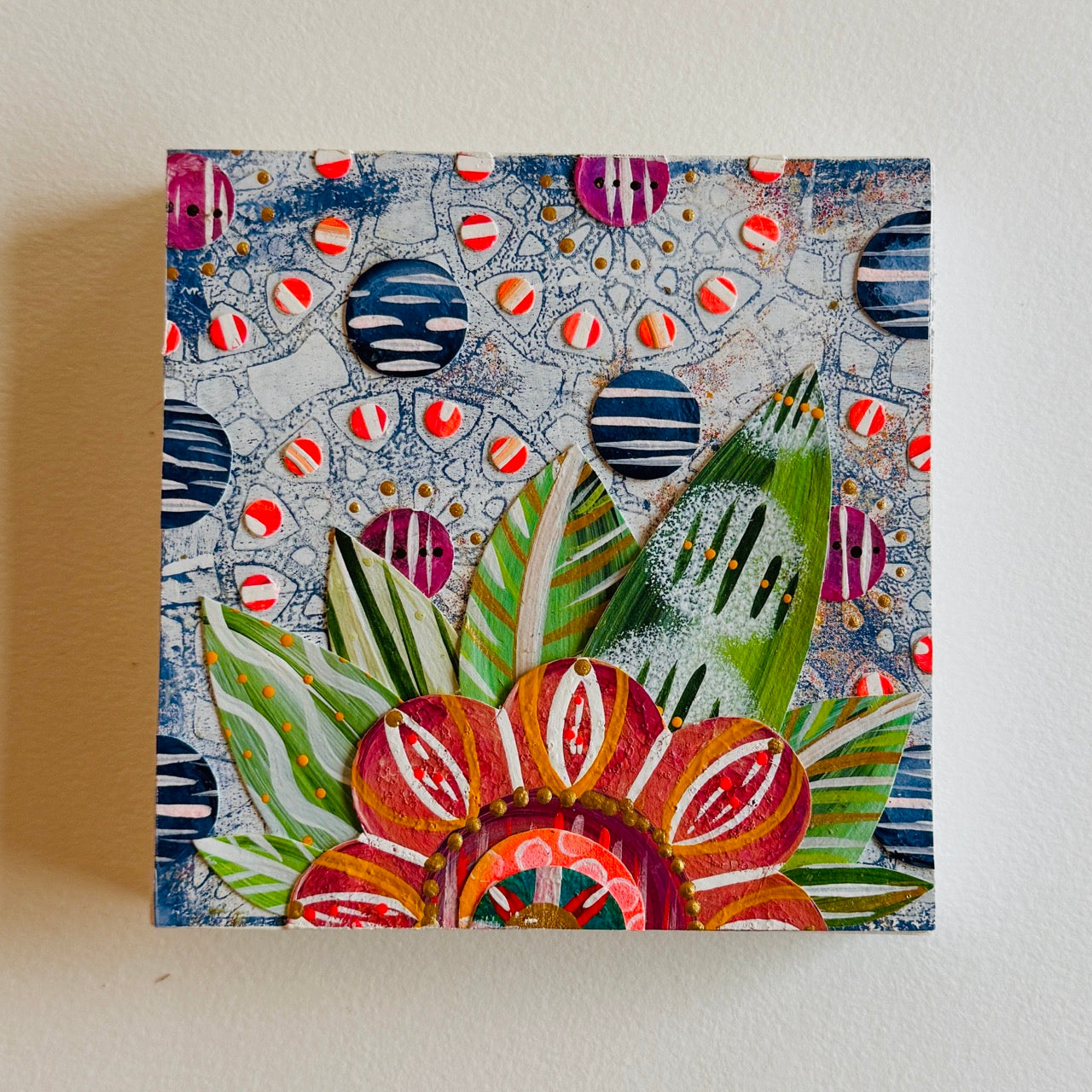 Small square wood panel art with a bold patterned floral design and hand-painted collage elements.