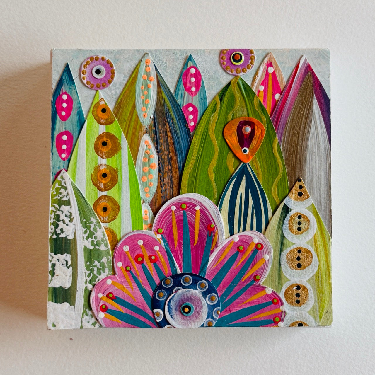 Small square wood panel art with a bold patterned floral design and hand-painted collage elements.
