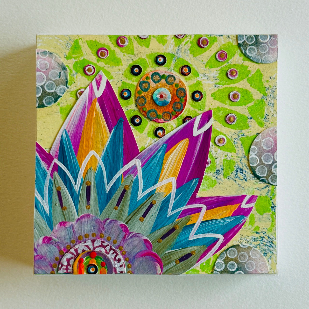 Small square wood panel art with a bold patterned floral design and hand-painted collage elements.