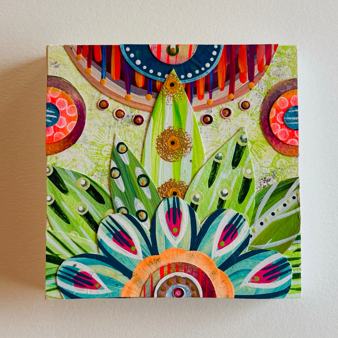 Small square wood panel art with a bold patterned floral design and hand-painted collage elements.