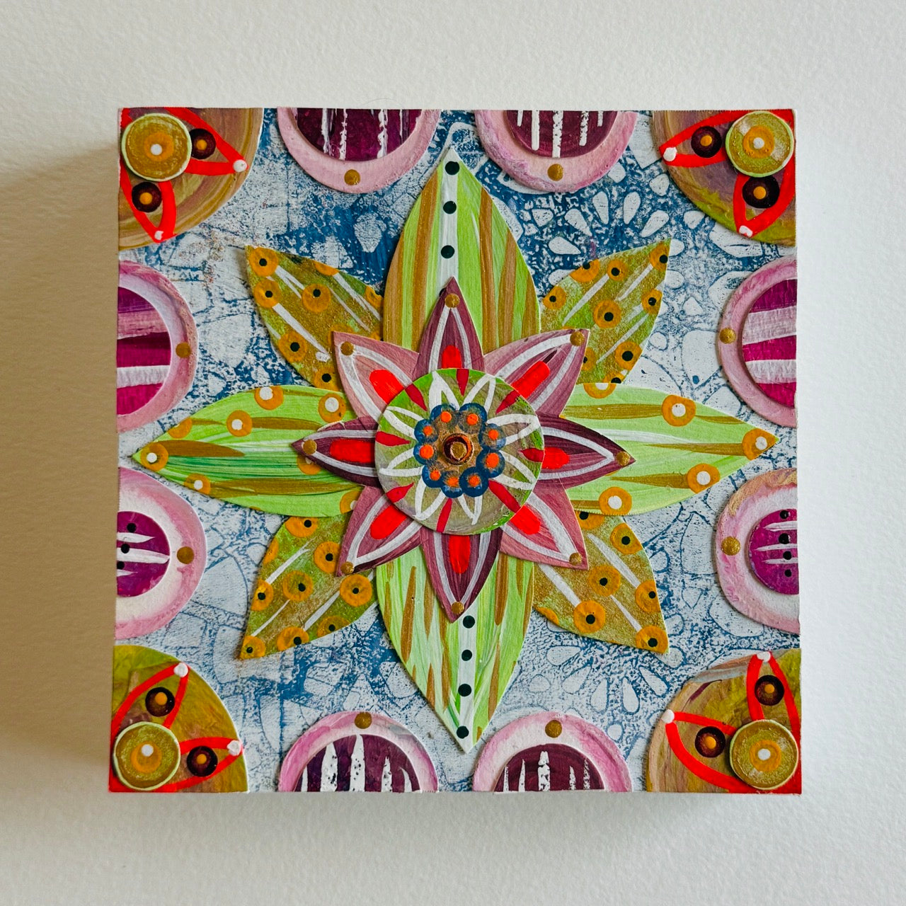 Small square wood panel art with a bold patterned floral design and hand-painted collage elements.